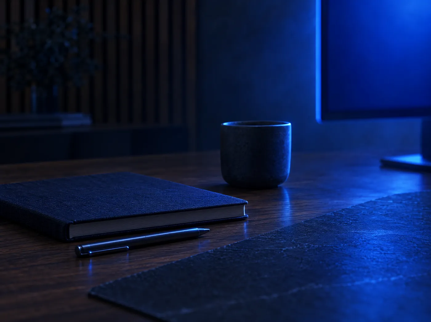 Mesa de trabalho em um estúdio escuro, iluminada pela luz azul de um monitor
